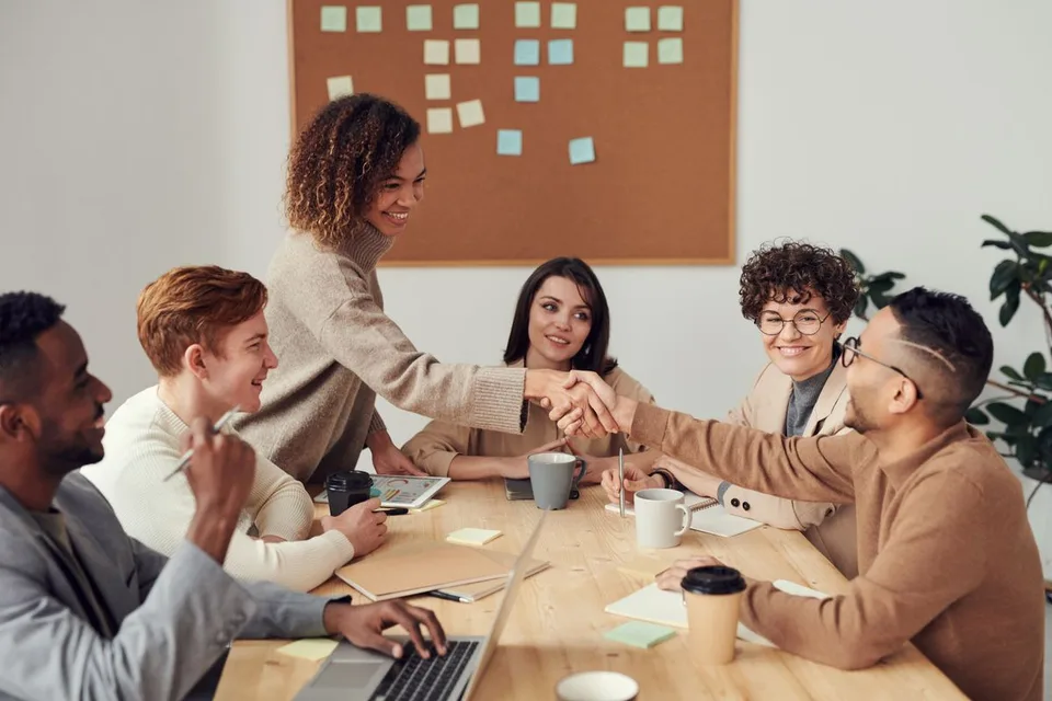 Stock photograph of people discussing ideas around a work table